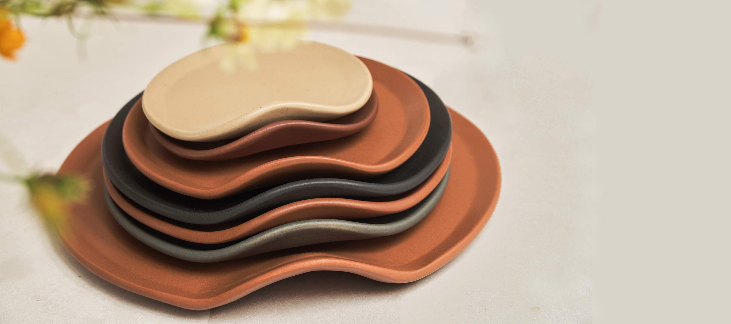 Stack of soft form ceramic dishware with mid-century glazes
